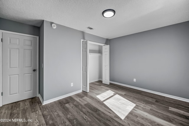 unfurnished bedroom featuring dark hardwood / wood-style flooring and a textured ceiling