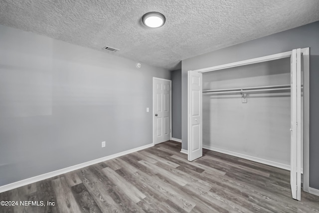 unfurnished bedroom with a closet, a textured ceiling, and hardwood / wood-style flooring