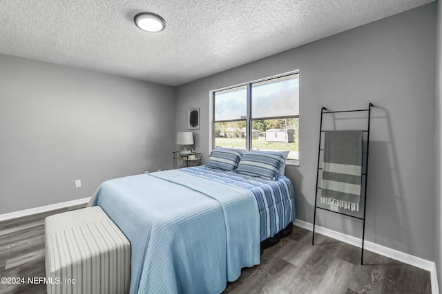 bedroom featuring dark hardwood / wood-style flooring and a textured ceiling