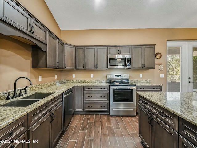 kitchen with appliances with stainless steel finishes, dark brown cabinetry, sink, dark hardwood / wood-style floors, and lofted ceiling