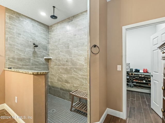 bathroom featuring tiled shower, wood-type flooring, and a textured ceiling