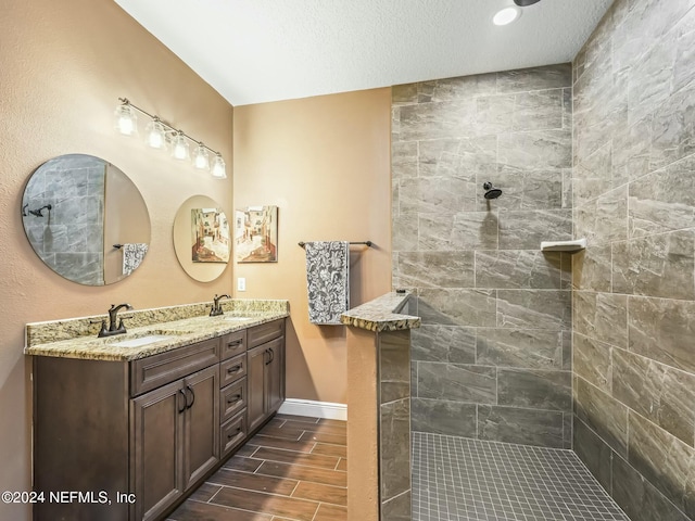 bathroom featuring a tile shower, vanity, wood-type flooring, and a textured ceiling