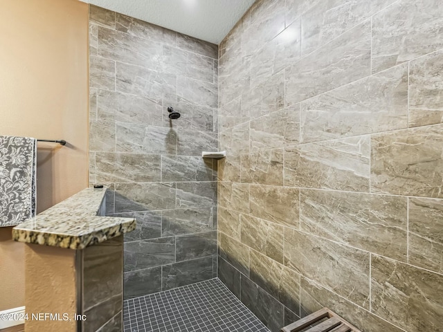 bathroom with a tile shower and a textured ceiling