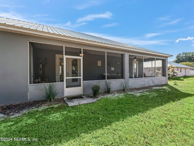 rear view of property with a sunroom and a lawn