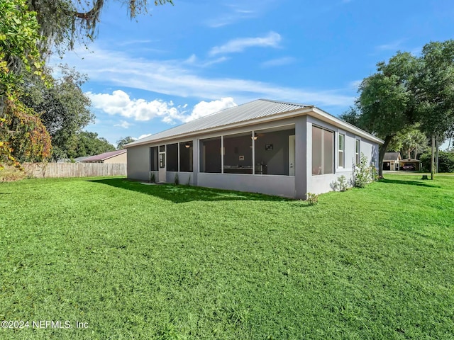 back of property with a sunroom and a yard