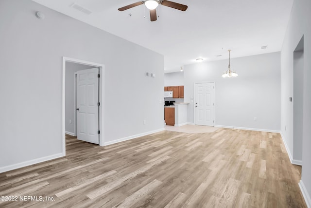 unfurnished living room featuring ceiling fan with notable chandelier and light hardwood / wood-style floors