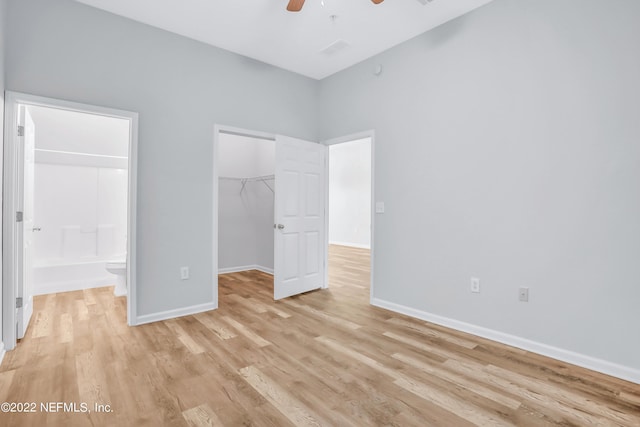 unfurnished bedroom with ensuite bath, ceiling fan, light hardwood / wood-style flooring, a walk in closet, and a closet