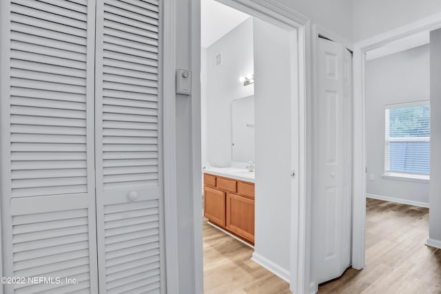 corridor with light hardwood / wood-style flooring and sink