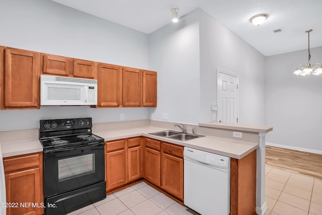 kitchen with white appliances, sink, decorative light fixtures, a notable chandelier, and kitchen peninsula