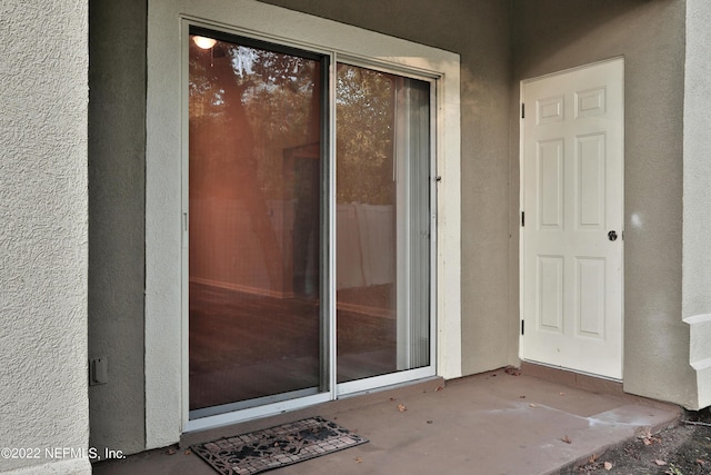 view of exterior entry with a patio