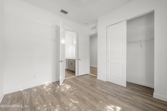 unfurnished bedroom with a closet and light wood-type flooring