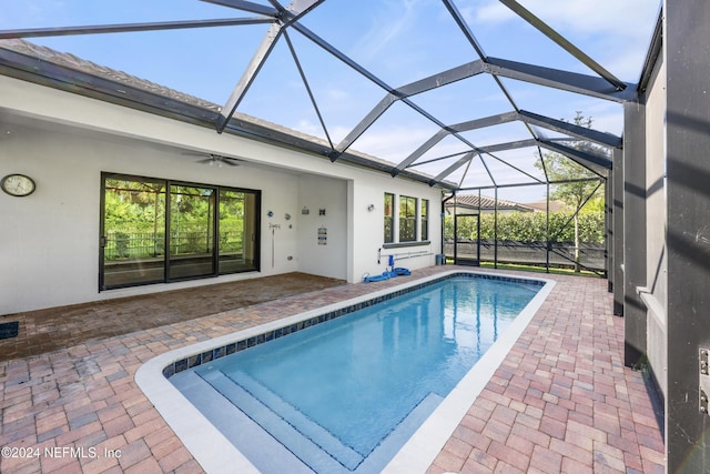 view of swimming pool with a patio area, ceiling fan, and glass enclosure