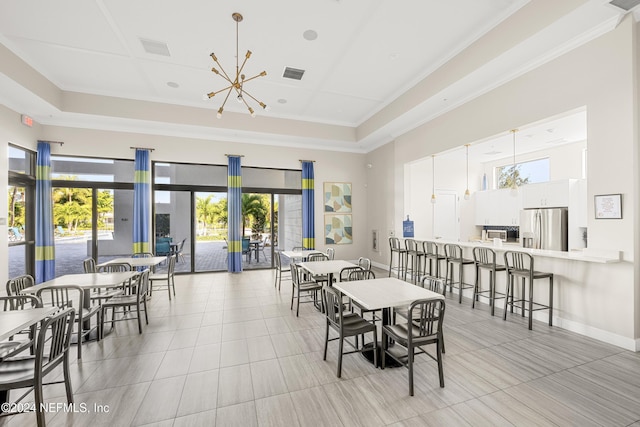 dining area with a towering ceiling, a chandelier, ornamental molding, a raised ceiling, and french doors