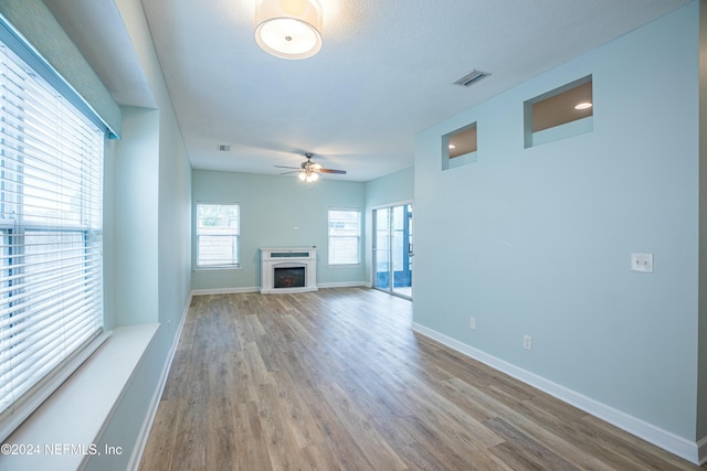 unfurnished living room with ceiling fan and wood-type flooring