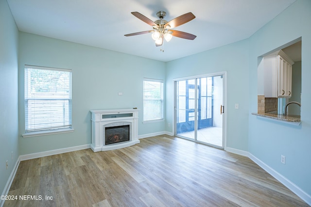 unfurnished living room with ceiling fan, sink, and light hardwood / wood-style flooring