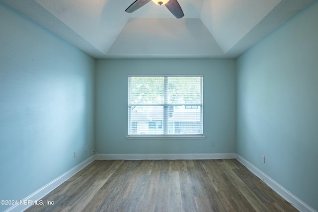 unfurnished room with ceiling fan, dark wood-type flooring, a tray ceiling, and vaulted ceiling