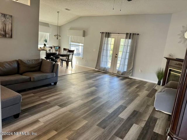 living room featuring french doors, dark hardwood / wood-style flooring, a textured ceiling, and vaulted ceiling