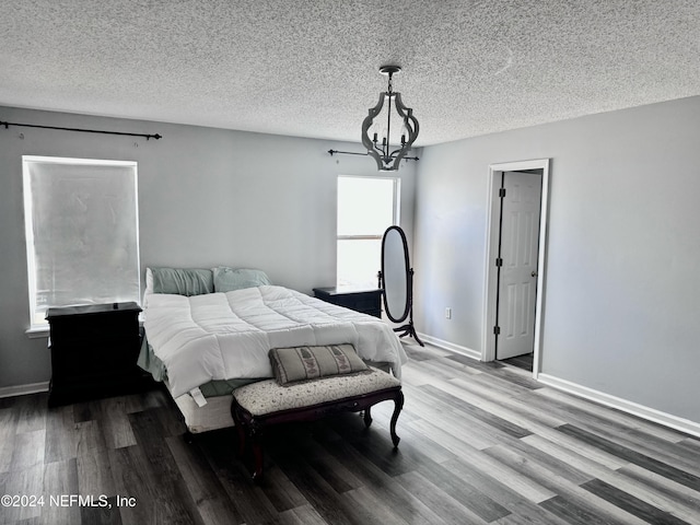 bedroom featuring hardwood / wood-style floors, a textured ceiling, and an inviting chandelier