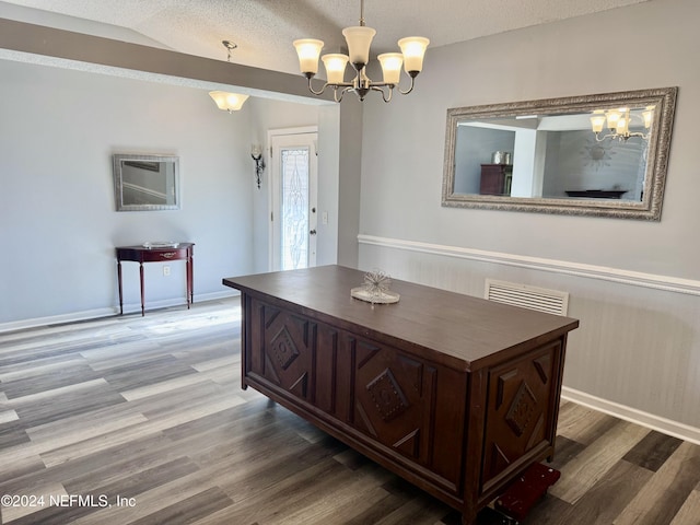 dining room with a notable chandelier, wood-type flooring, and a textured ceiling