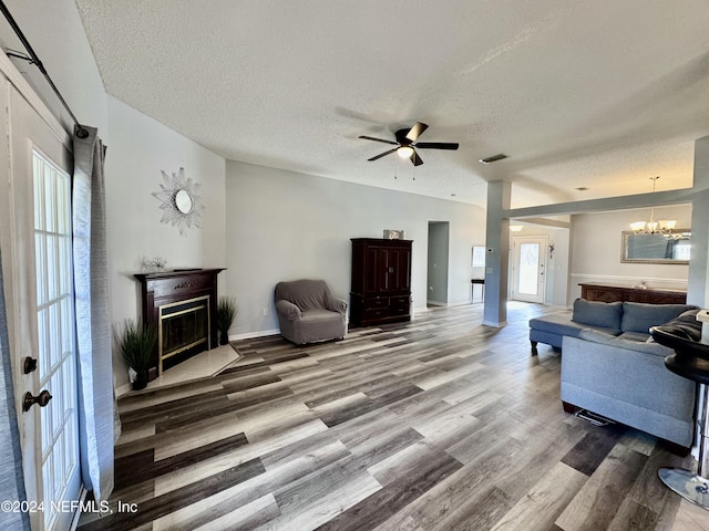 living room with hardwood / wood-style floors, ceiling fan with notable chandelier, and a textured ceiling