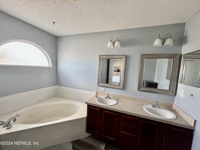 bathroom with a bathtub, vanity, hardwood / wood-style floors, and a textured ceiling