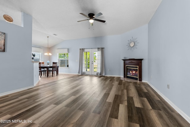 3130 Haverhill Ct, Green Cove Springs, FL 32043 - unfurnished living room featuring wood finished floors, baseboards, vaulted ceiling, a glass covered fireplace, and ceiling fan with notable chandelier