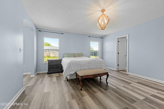3130 Haverhill Ct, Green Cove Springs, FL 32043 - bedroom featuring light wood finished floors, baseboards, an inviting chandelier, arched walkways, and a textured ceiling