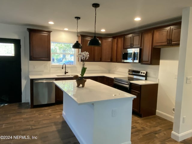 kitchen with stainless steel appliances, dark wood-type flooring, sink, a kitchen island, and hanging light fixtures