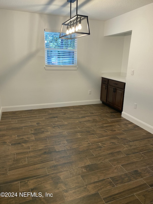 unfurnished dining area with dark hardwood / wood-style flooring and a textured ceiling