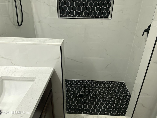 bathroom with tiled shower and vanity