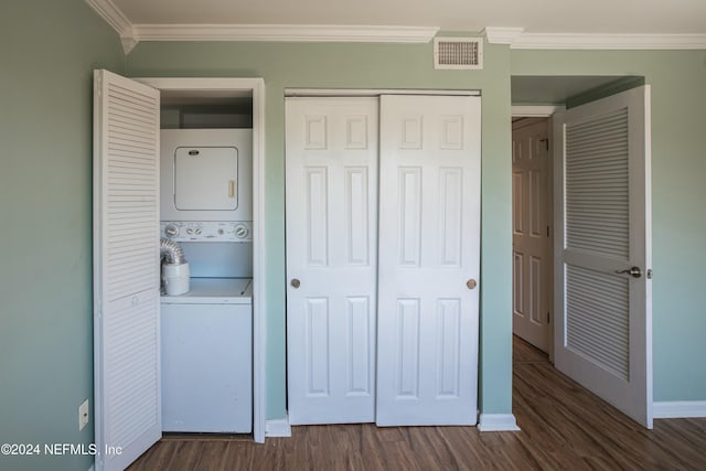 washroom featuring dark hardwood / wood-style flooring, stacked washing maching and dryer, and crown molding