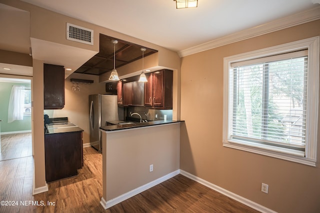 kitchen featuring wood-type flooring, decorative light fixtures, stainless steel refrigerator, and crown molding