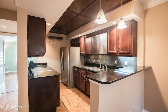 kitchen featuring sink, hanging light fixtures, stainless steel fridge, light wood-type flooring, and kitchen peninsula