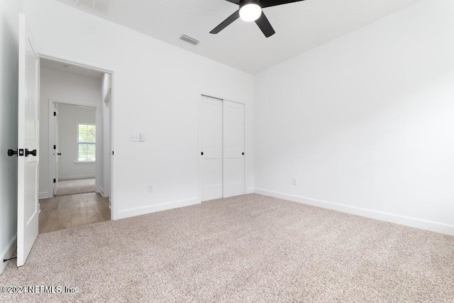 unfurnished bedroom featuring ceiling fan, a closet, and light carpet