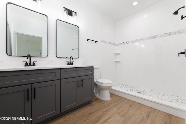 bathroom featuring a tile shower, toilet, vanity, and hardwood / wood-style flooring