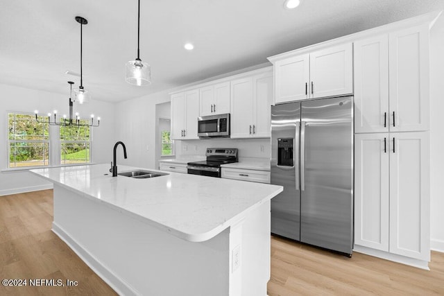 kitchen with light wood-type flooring, stainless steel appliances, sink, a center island with sink, and white cabinets