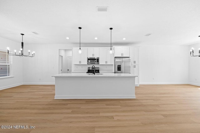 kitchen featuring stainless steel appliances, pendant lighting, an inviting chandelier, light hardwood / wood-style flooring, and white cabinets