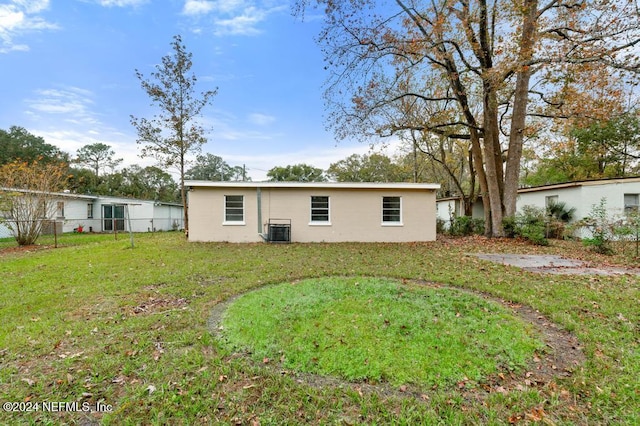 rear view of house featuring a lawn and central AC