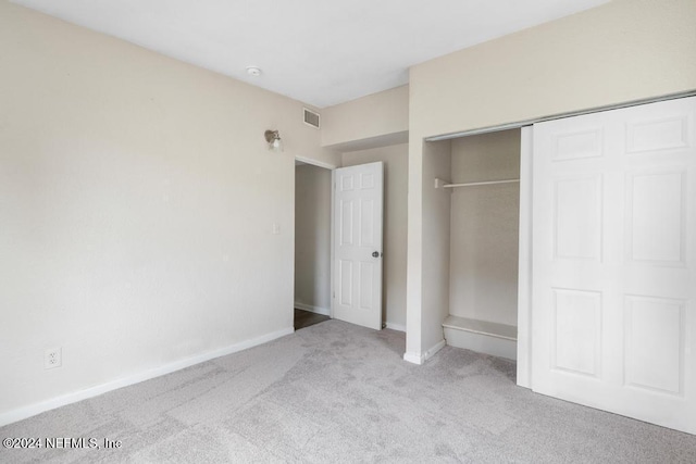 unfurnished bedroom featuring light colored carpet and a closet