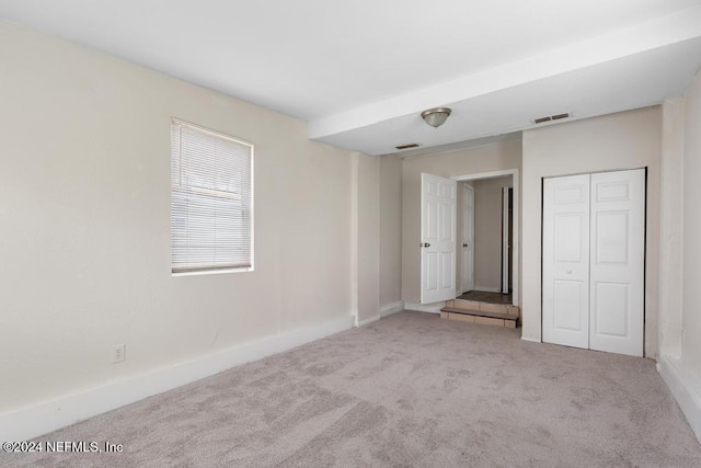 unfurnished bedroom featuring light carpet and a closet