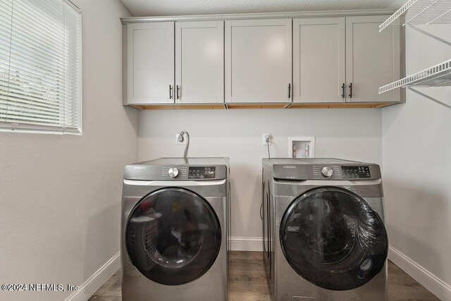 washroom featuring cabinets, washing machine and dryer, and dark wood-type flooring