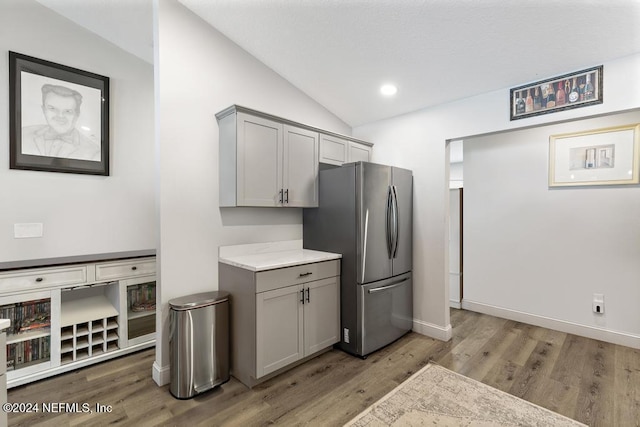 kitchen featuring gray cabinets, stainless steel refrigerator, lofted ceiling, and light hardwood / wood-style floors