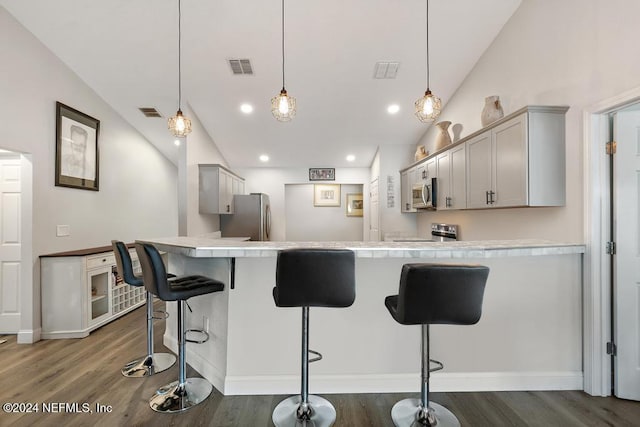 kitchen featuring gray cabinetry, lofted ceiling, a kitchen breakfast bar, decorative light fixtures, and stainless steel appliances