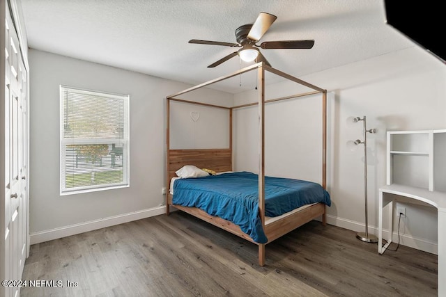 bedroom with ceiling fan, dark hardwood / wood-style flooring, a textured ceiling, and a closet