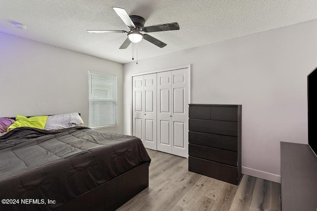 bedroom featuring a closet, ceiling fan, light hardwood / wood-style flooring, and a textured ceiling