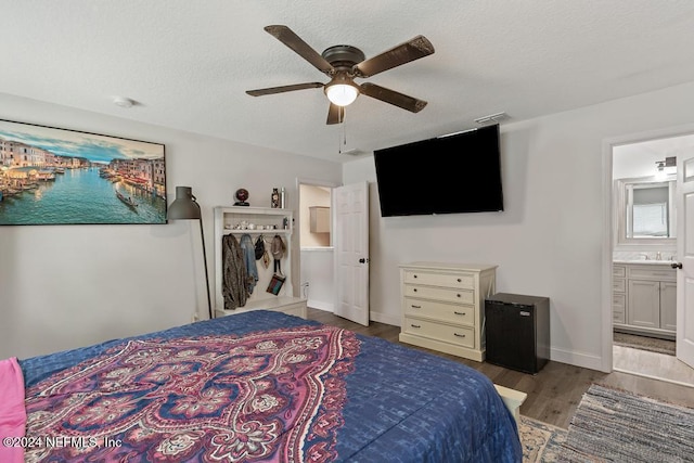 bedroom with ensuite bath, ceiling fan, a textured ceiling, light hardwood / wood-style floors, and a closet