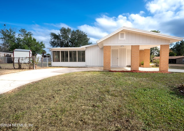 view of front of house featuring a carport, a sunroom, and a front lawn