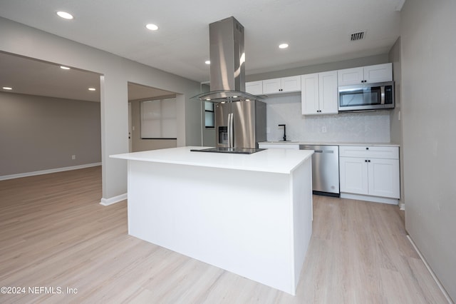 kitchen with backsplash, white cabinets, appliances with stainless steel finishes, a kitchen island, and island exhaust hood