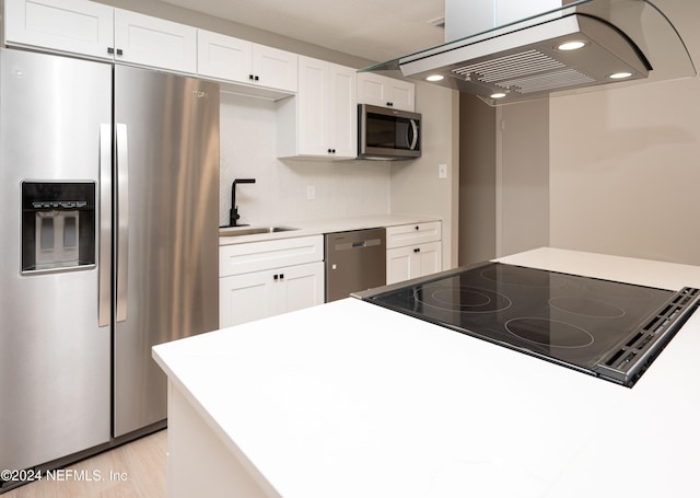 kitchen featuring island exhaust hood, sink, white cabinets, and appliances with stainless steel finishes