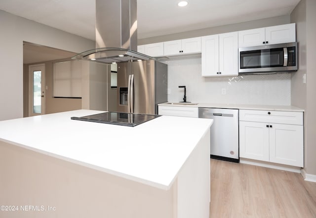 kitchen with light hardwood / wood-style flooring, decorative backsplash, appliances with stainless steel finishes, white cabinetry, and island exhaust hood